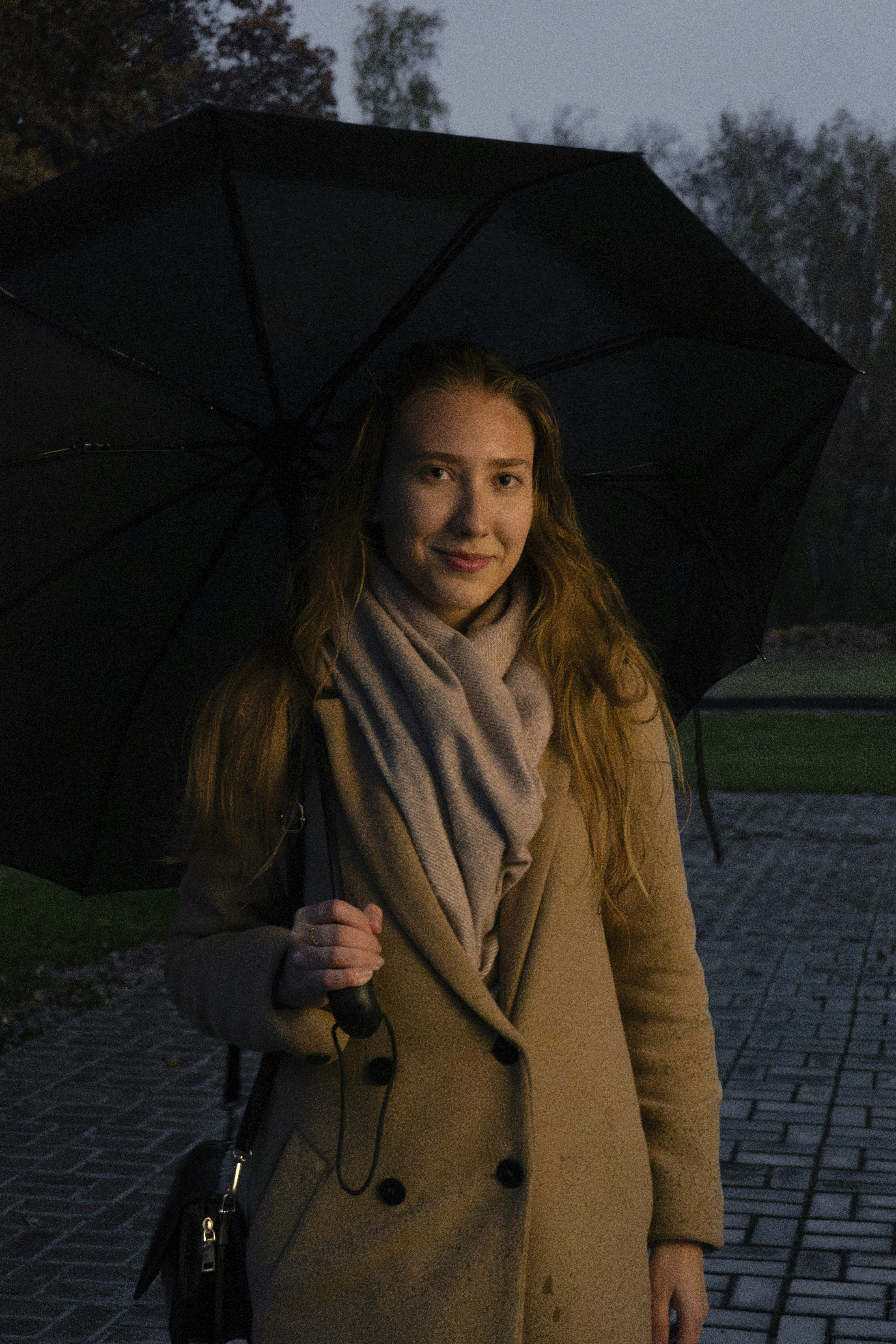 a woman in a coat and scarf holding an umbrella