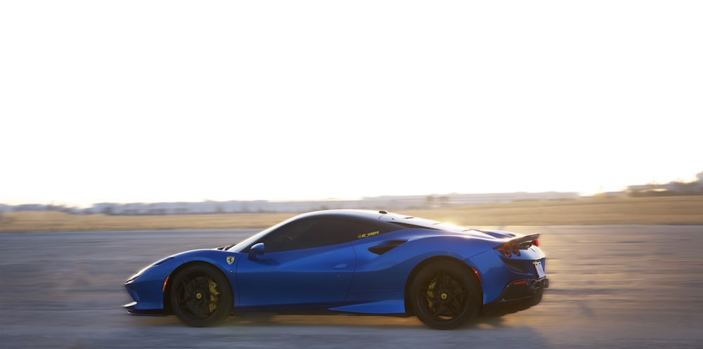 a blue sports car driving down a road