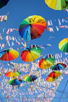Colorful banners and umbul-umbul hanging outdoors in bright sunlight.