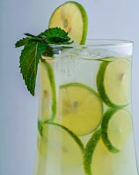 A refreshing tropical drink garnished with a slice of lime and mint leaves.