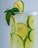 A refreshing beverage with multiple slices of lime floating in the liquid. Fresh mint leaves are garnished on the rim of the glass, adding a touch of green. The drink is chilled with visible ice cubes, all contained within a clear glass.