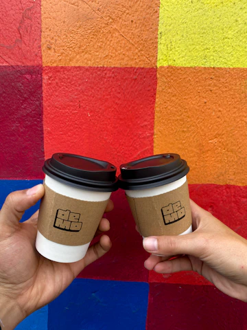 Hands holding eco-friendly disposable cups with a restaurant background.