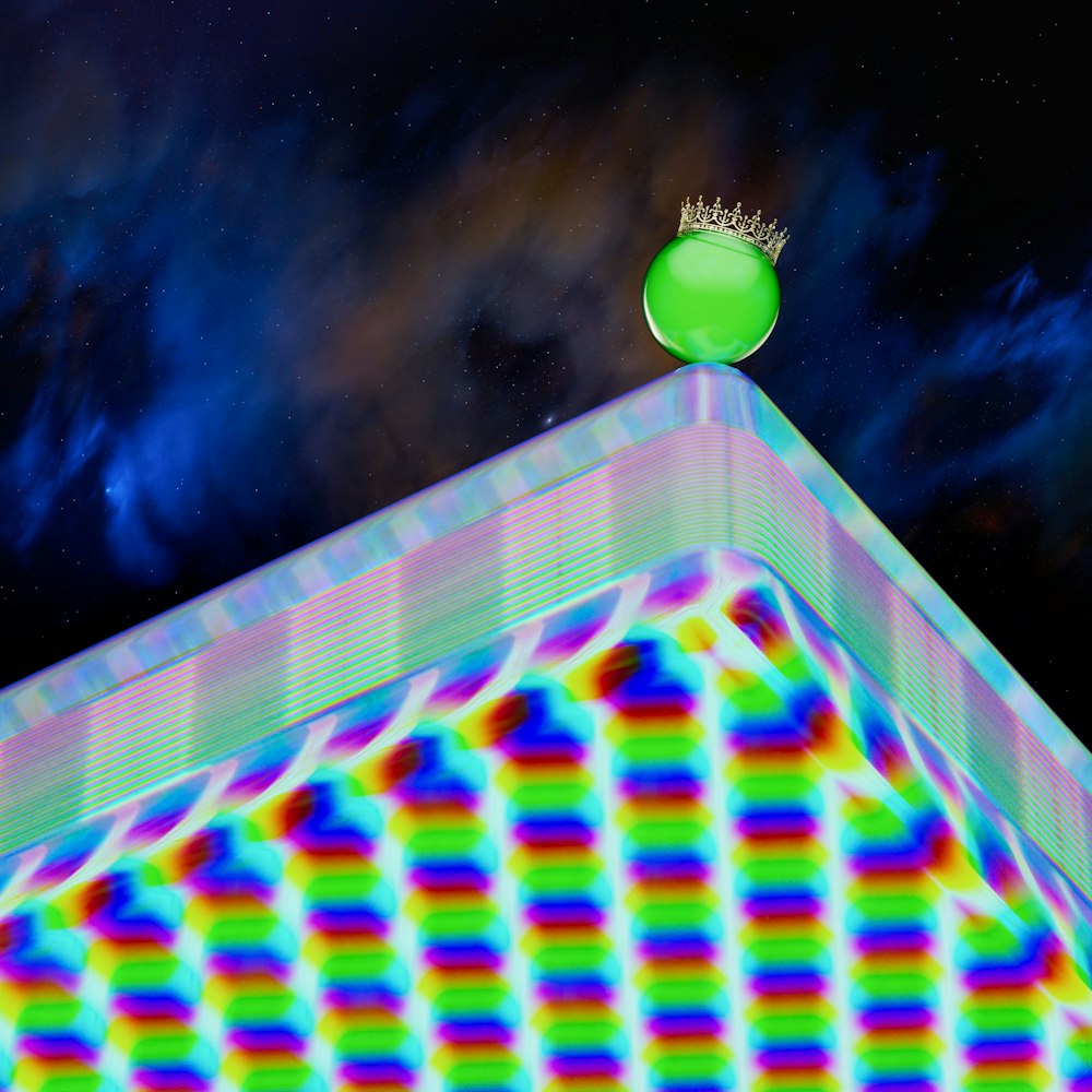 a green ball sitting on top of a colorful pyramid