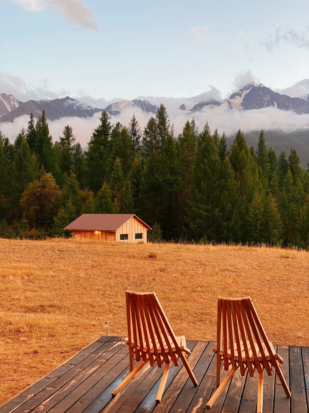 two wooden chairs sitting on top of a wooden deck