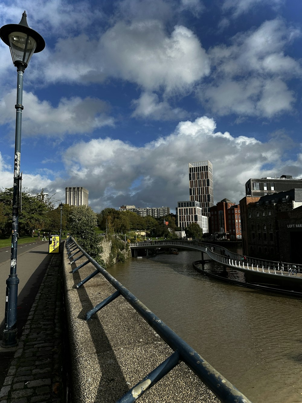 a street light sitting next to a river under a cloudy sky