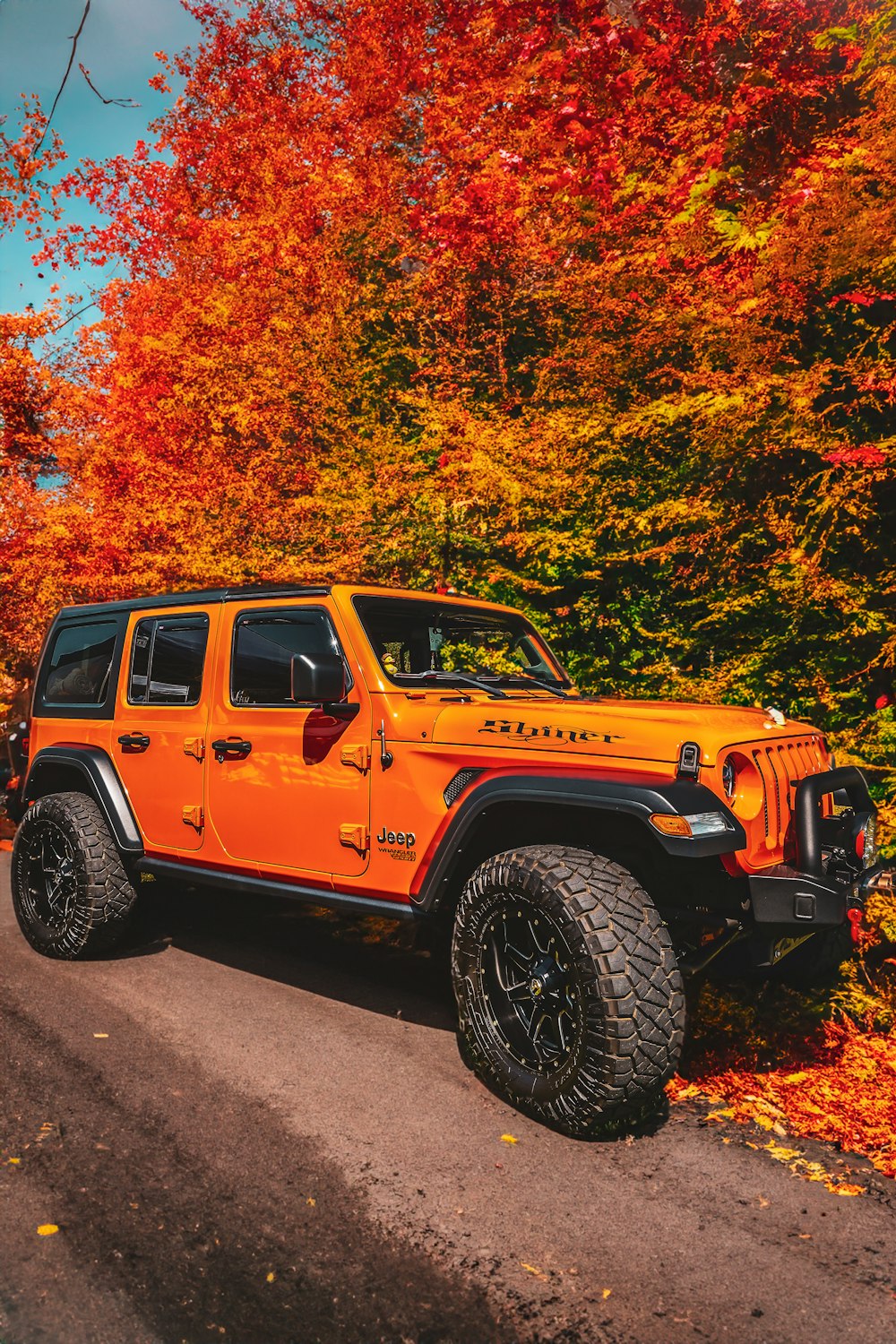a bright orange jeep parked on the side of a road