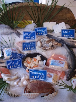 Fresh seafood assortment displayed on natural wooden table with green leaves