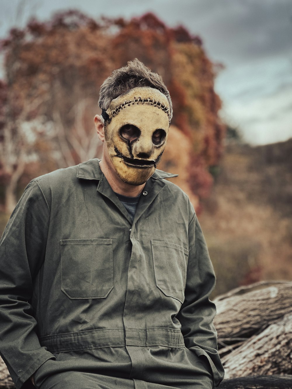 a man wearing a mask sitting on a log