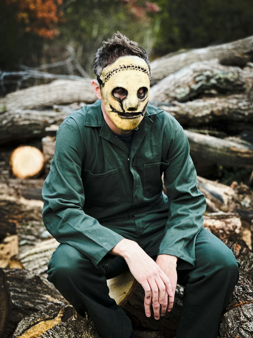 a man wearing a mask sitting on a log