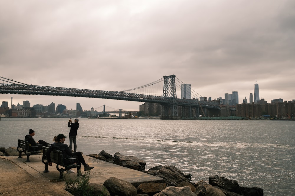 a group of people sitting on benches near the water