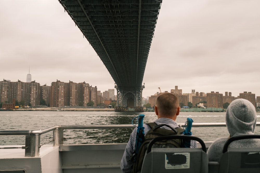 two people sitting on a boat under a bridge