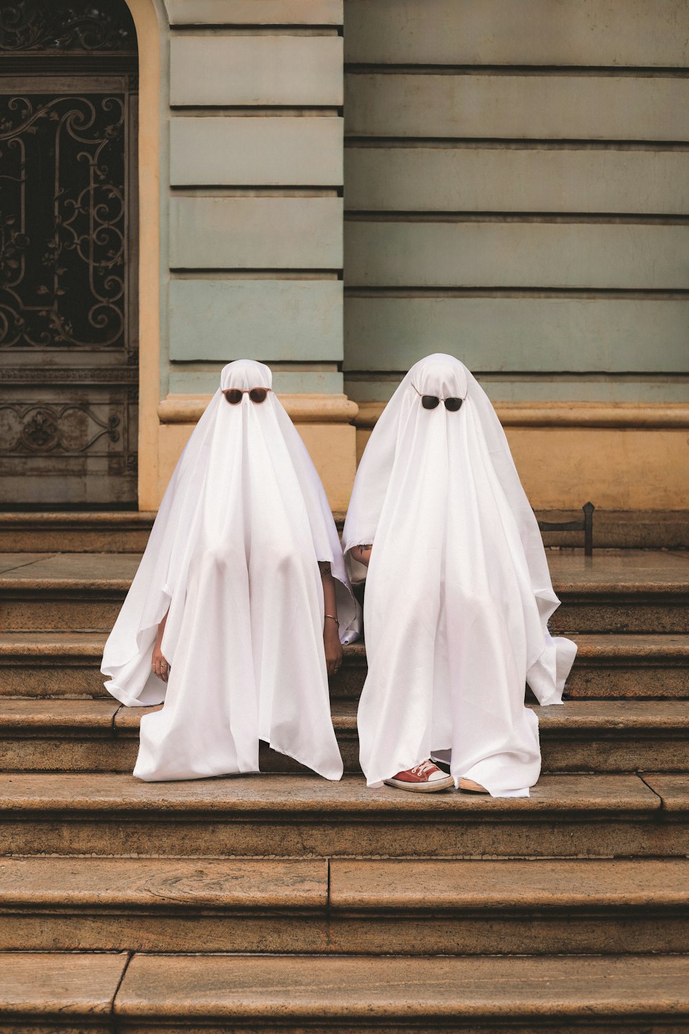 two people in white ghost costumes sitting on steps