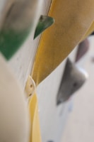 Close-up view of various rock climbing holds on a climbing wall, featuring textured surfaces and different shapes in a vertical alignment.