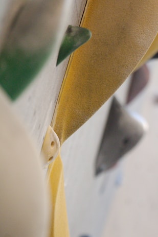 Close-up view of various rock climbing holds on a climbing wall, featuring textured surfaces and different shapes in a vertical alignment.
