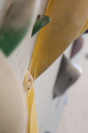 Close-up view of various rock climbing holds on a climbing wall, featuring textured surfaces and different shapes in a vertical alignment.