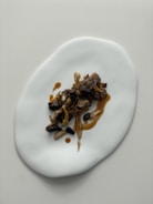 Close-up of a gourmet dish artfully plated on a minimalist white background.