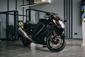 A customer happily inspecting the details of a matte black bike inside Varsha Velocity showroom