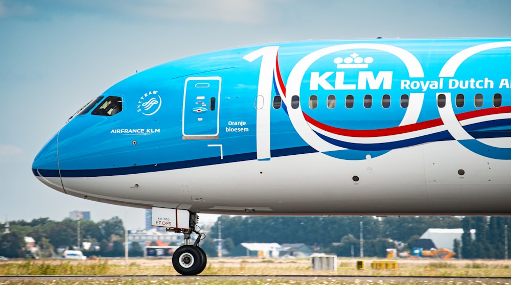 a large blue and white jetliner sitting on top of an airport runway