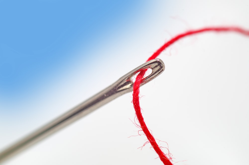 a close up of a needle with a red thread