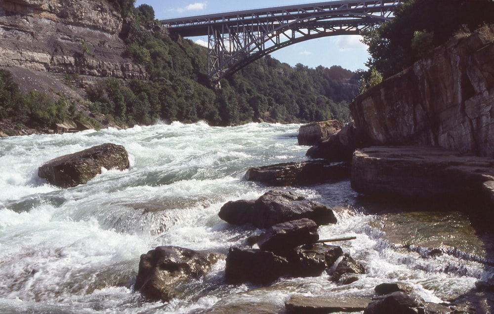 a bridge over a river with rapids and rocks
