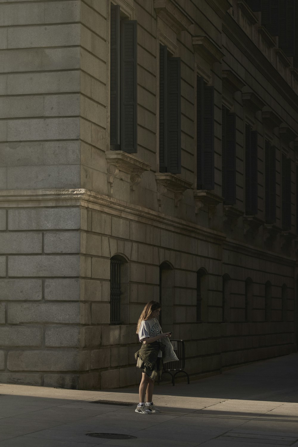 a woman standing on a sidewalk next to a building
