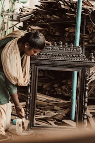 An artisan carefully carving a custom mirror frame in a warm, inviting workshop.