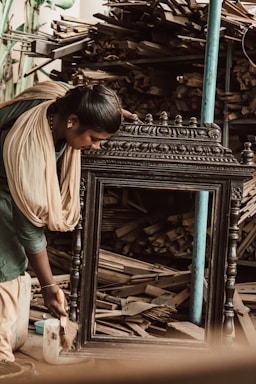 Close-up of a craftsman carefully restoring a vintage painting frame in a cozy workshop.