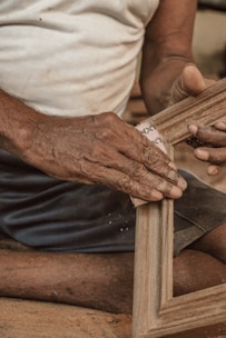 Close-up of hands sanding a wooden surface to smooth finish.