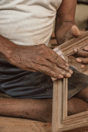 Detail of a craftsman sanding and preparing wooden window frame for painting.