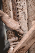 Close-up of a craftsman’s hands carving intricate patterns into warm-toned wood.