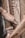 A person is engaged in wood carving, using a chisel to intricately engrave patterns into a piece of wood. The hands are weathered, suggesting experience or age, and the focus is on the detailed craftsmanship. There is a close-up view of tools and the carved wooden surface.