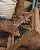 Close-up of hands crafting wooden furniture in a workshop.