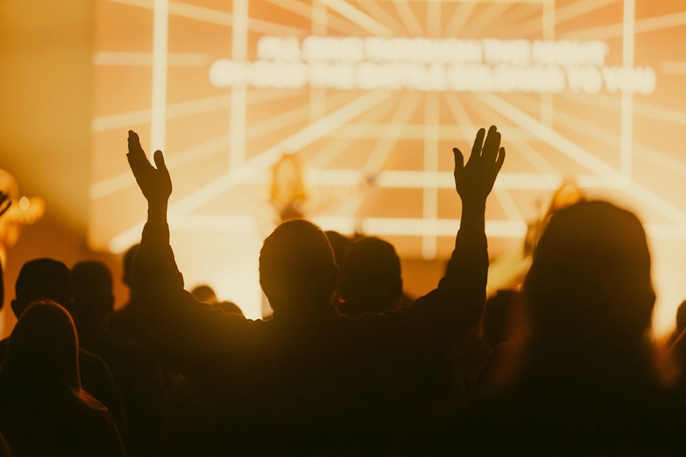 a crowd of people raising their hands in the air