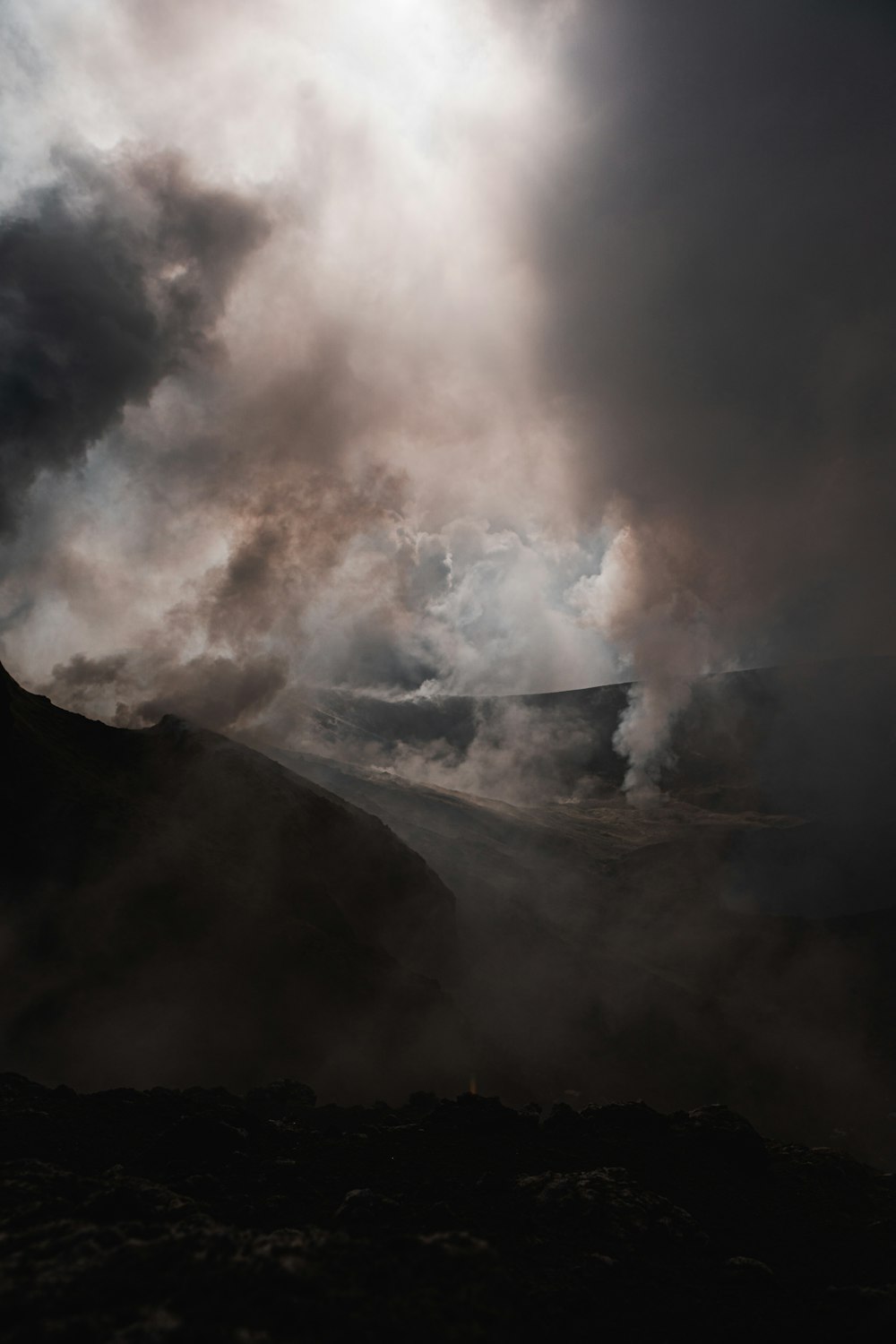 a black and white photo of smoke coming out of a mountain