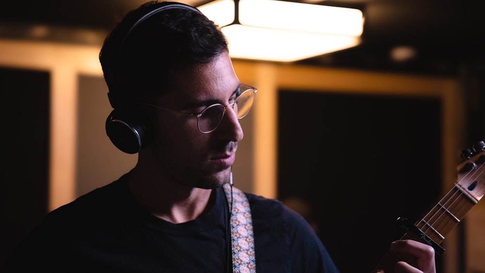 a man wearing headphones and holding a guitar