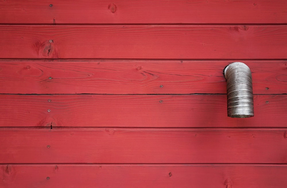 a red wall with a metal pipe on it