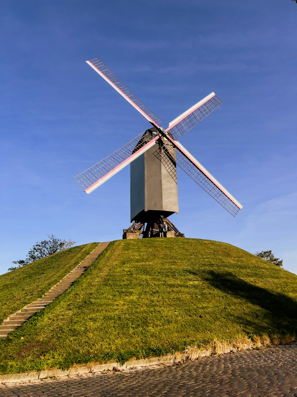 a windmill sitting on top of a lush green hillside