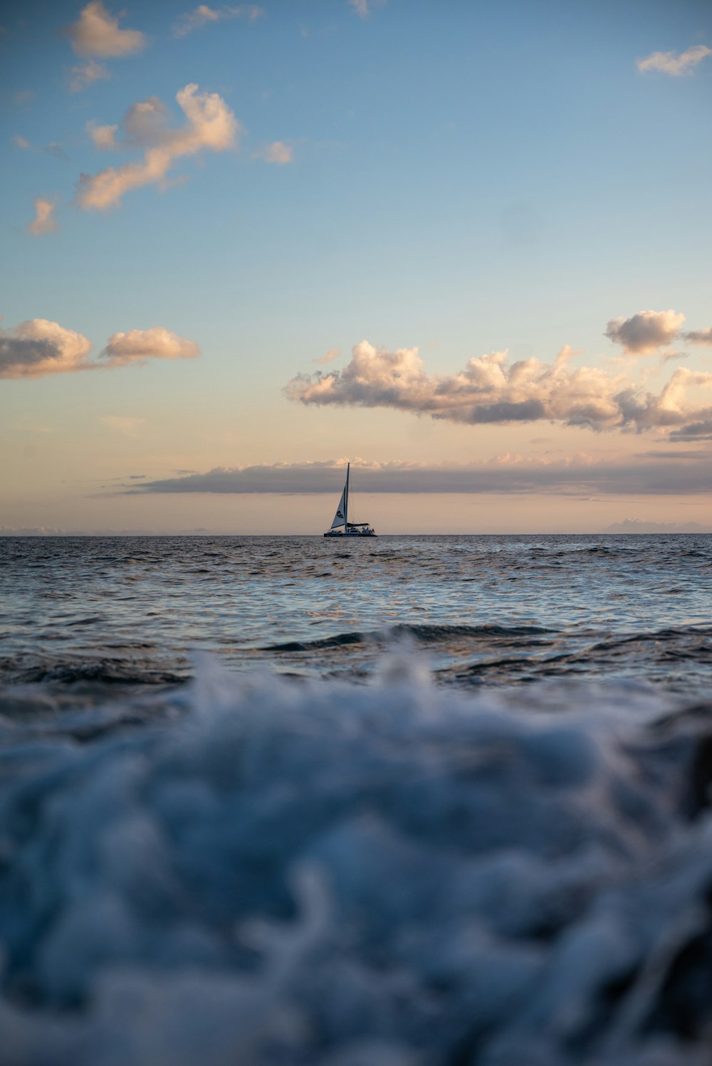 a sailboat sailing in the ocean at sunset