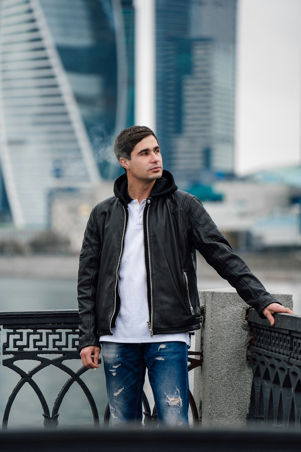 a man leaning against a wall with a city in the background