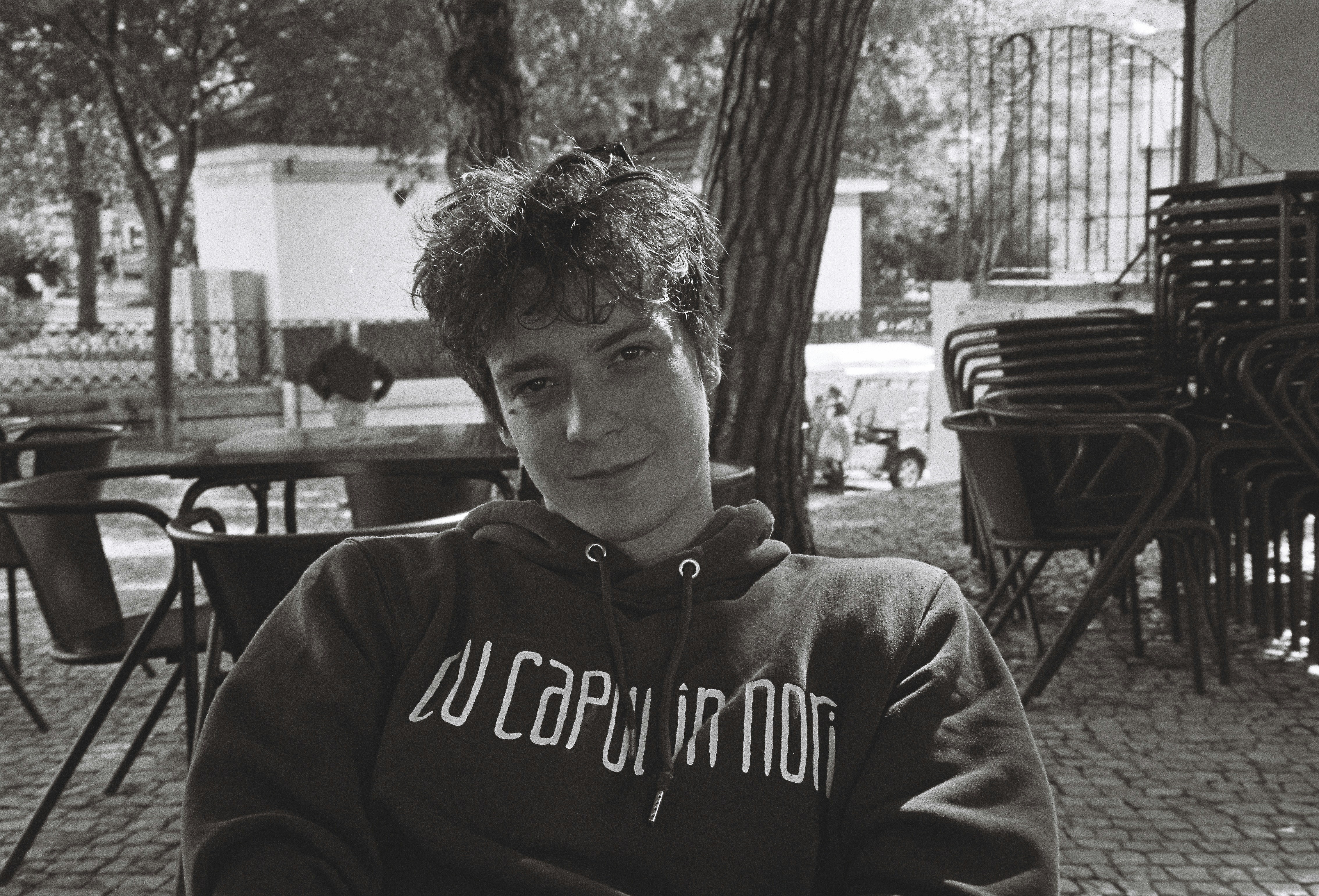 Fotomural a young man sitting at a table in a park