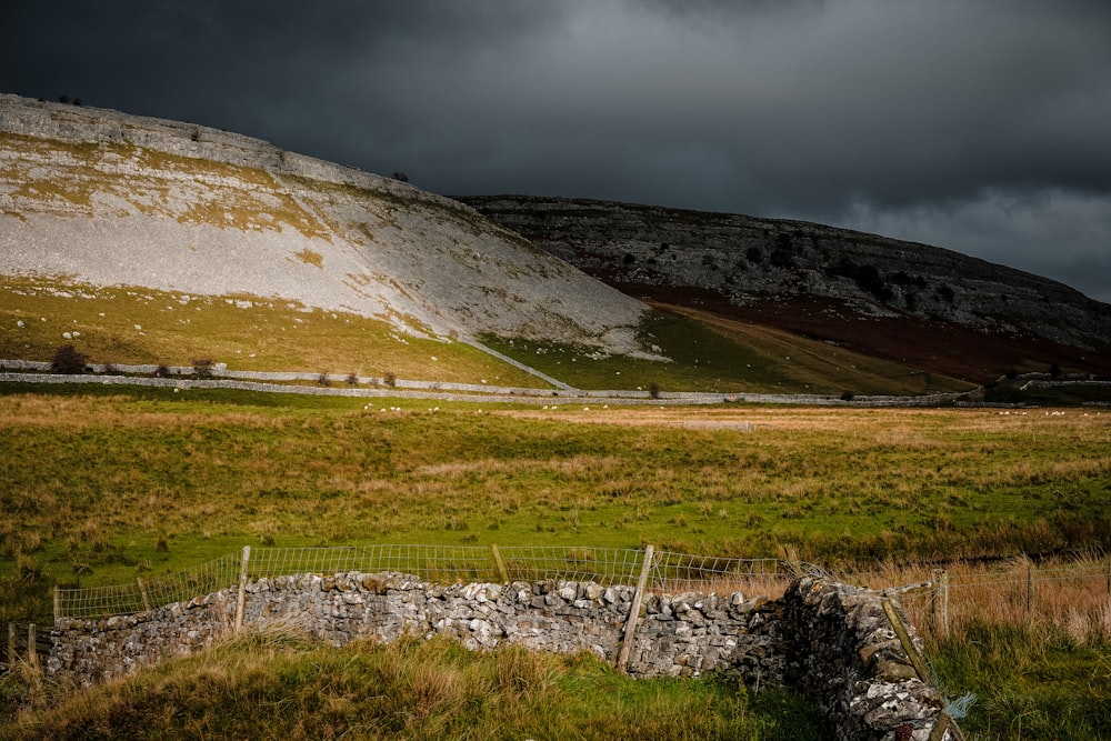 a field with a fence and a hill in the background