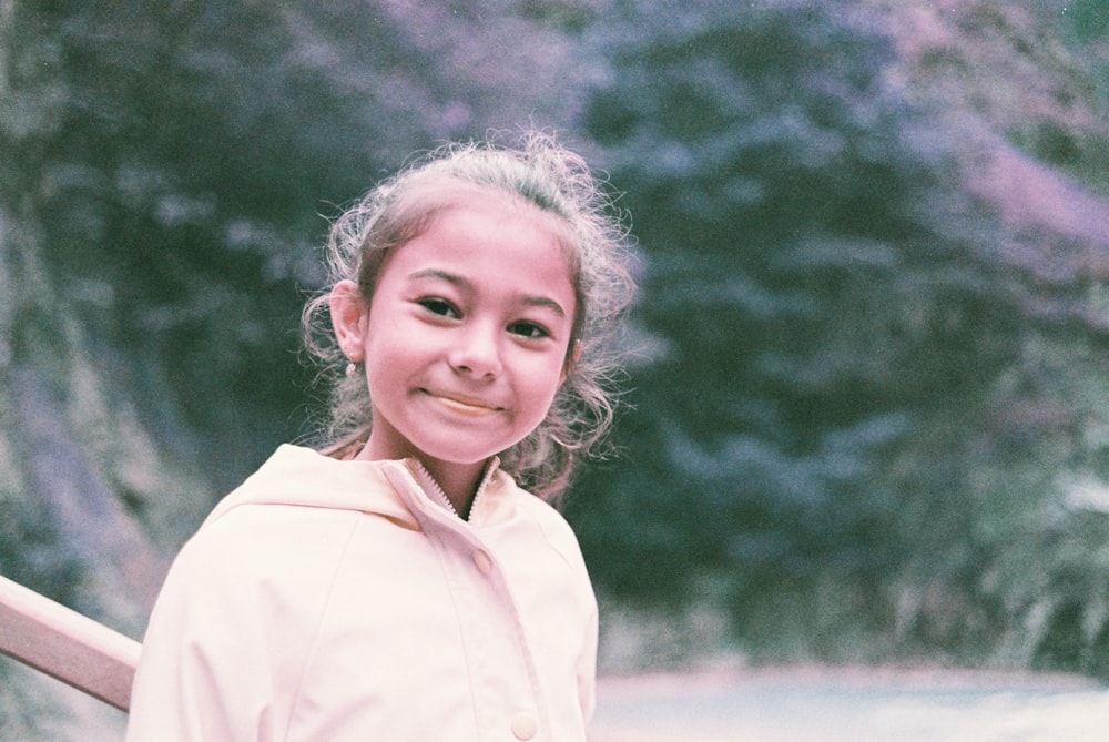 a young girl standing on a bridge next to a waterfall