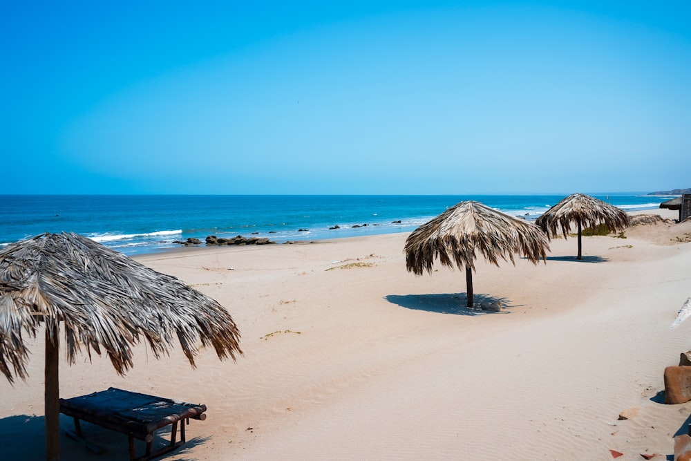 a sandy beach with umbrellas and a picnic table