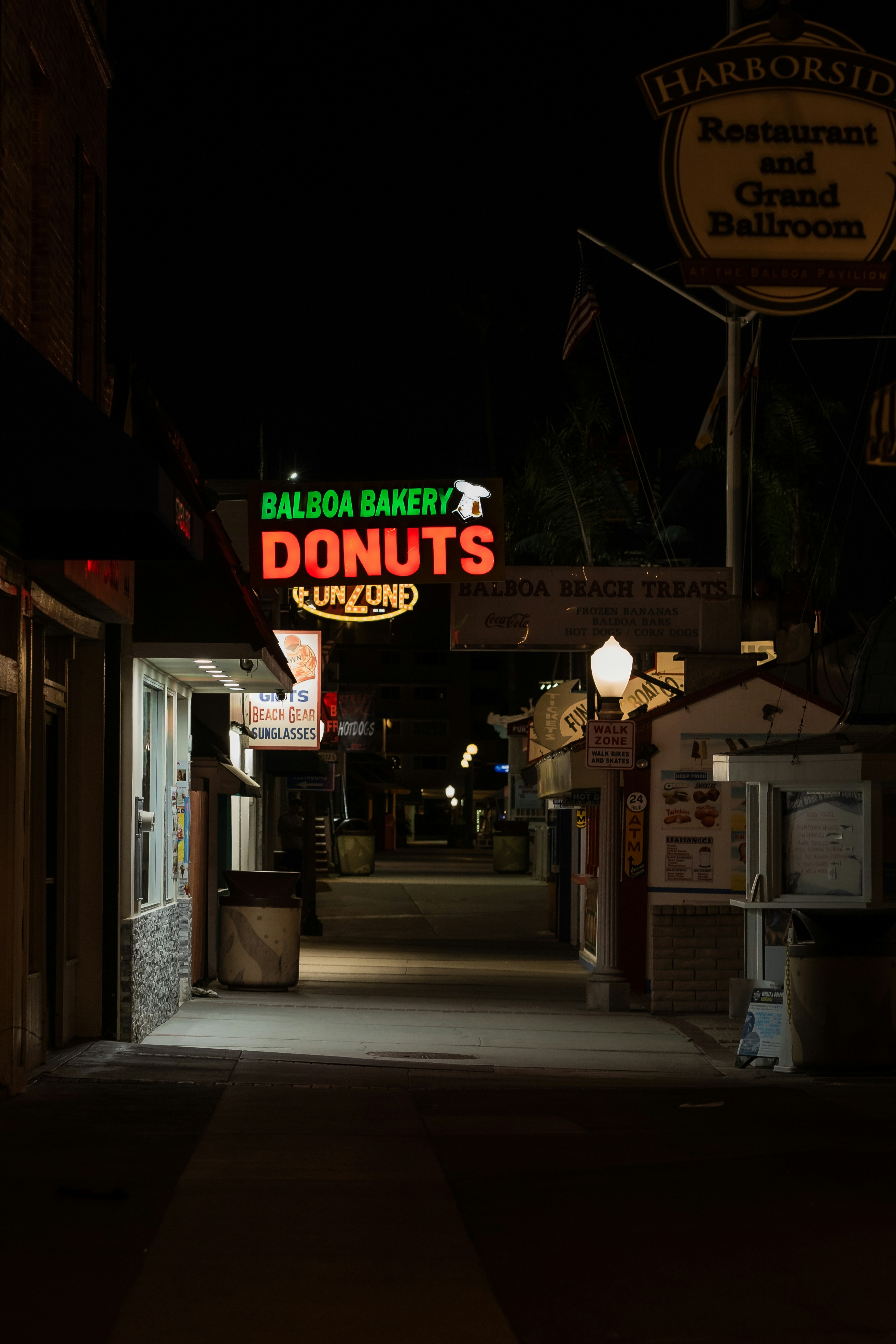 a dark alley way with a neon donuts sign