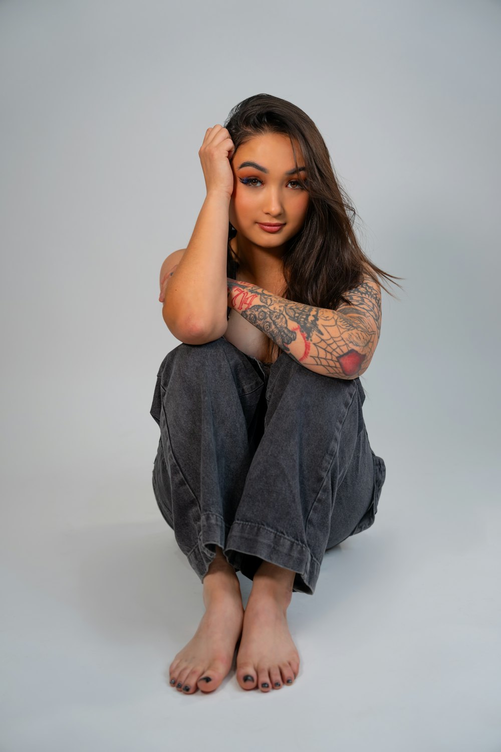 a woman with tattoos sitting on the ground