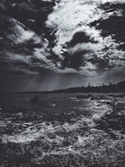 Storm clouds gathering above a windswept rocky coastline.