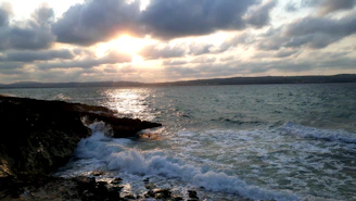 A beautifully framed coastal photograph capturing the golden light of sunset over Cape Ann's rocky shore.
