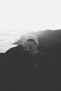 a black and white photo of a man covering his eyes