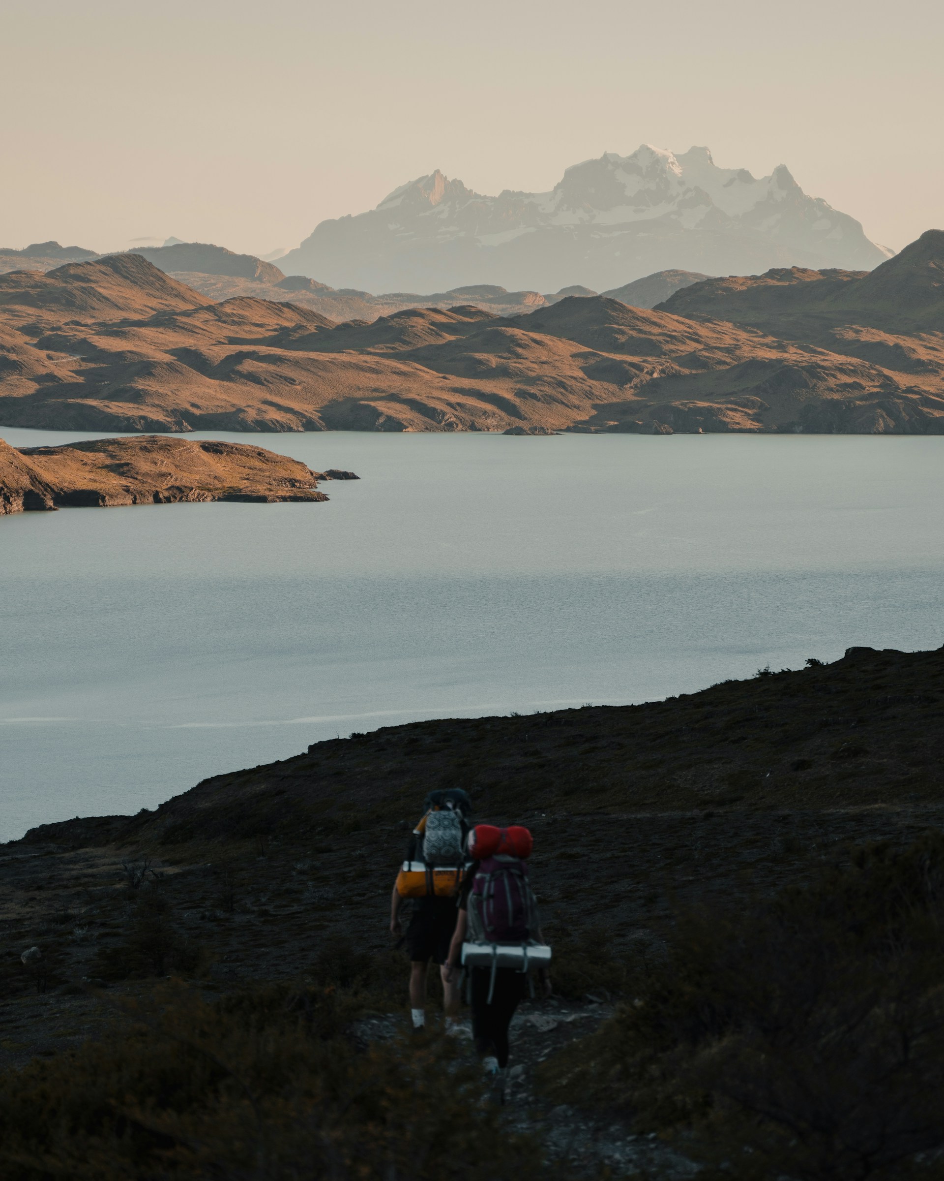 Hikers trekking along a mountain trail with panoramic views of the Calamuchita valley, capturing the spirit of adventure and tranquility.