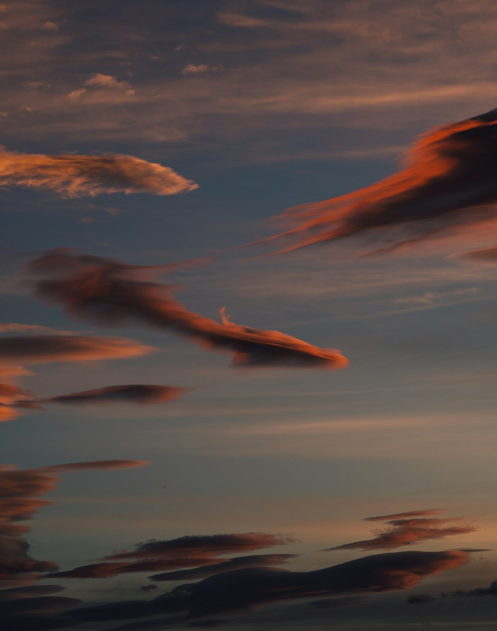 a plane flying in the sky at sunset